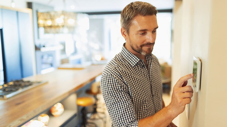 man adjusting digital thermostat at home